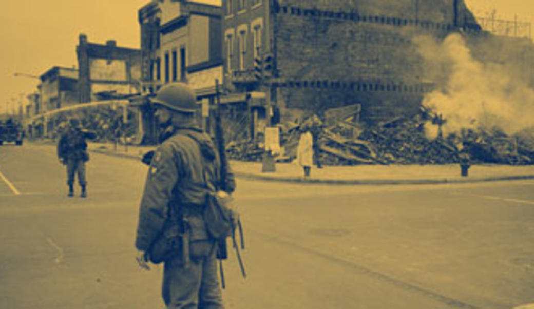 National guardsman in front of burned out building