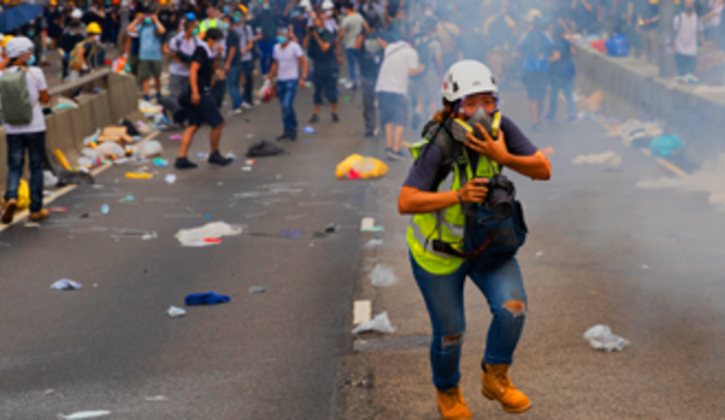 Protestor covering her mouth with tear gas swirling