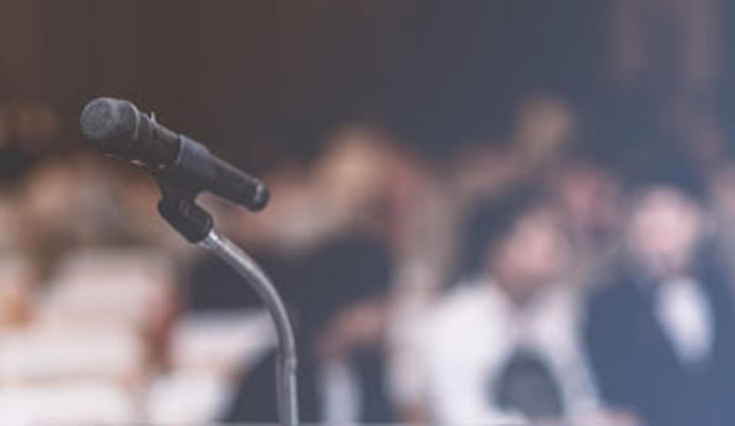 Closeup of a microphone, with a crowd in the background