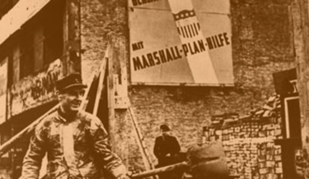 Man with shovel in front of German sign promoting Marshall Plan