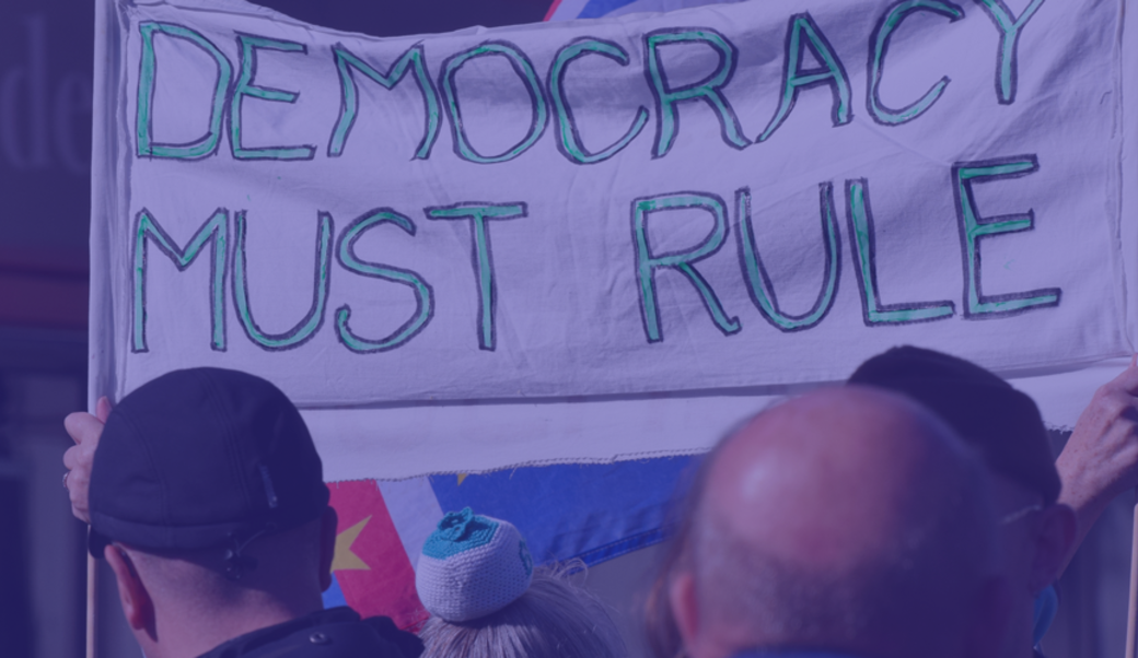 Protesters in London with a sign that says 'Democracy must rule'