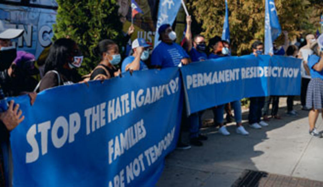 protestors holding large blue sign promoting residency