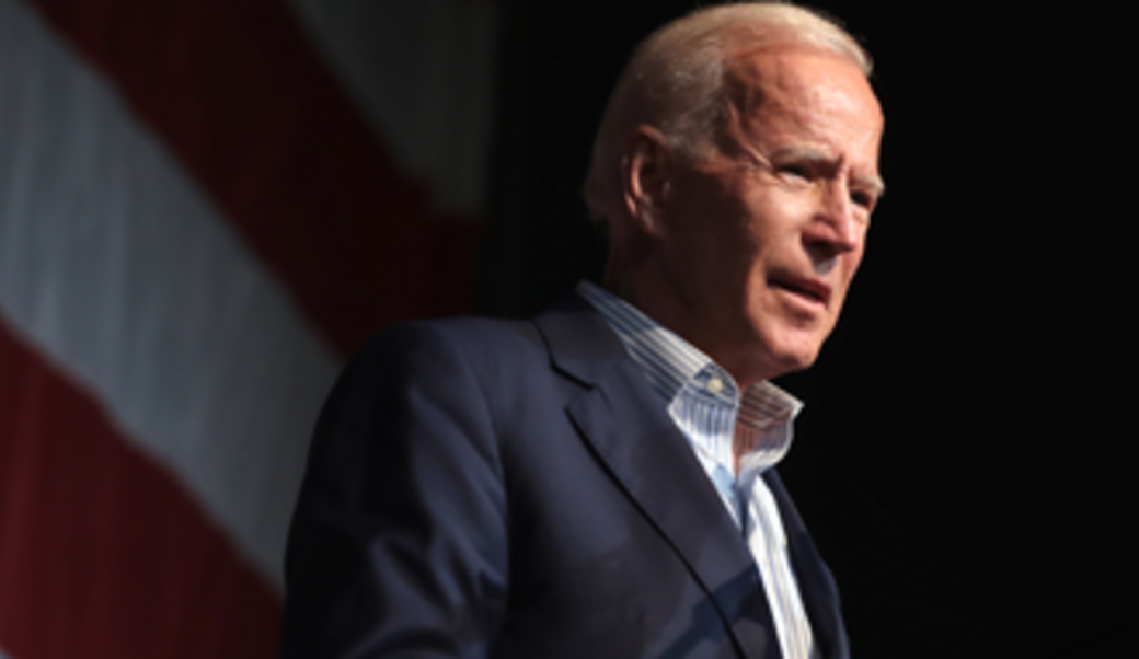 President Biden standing in front of a dark background