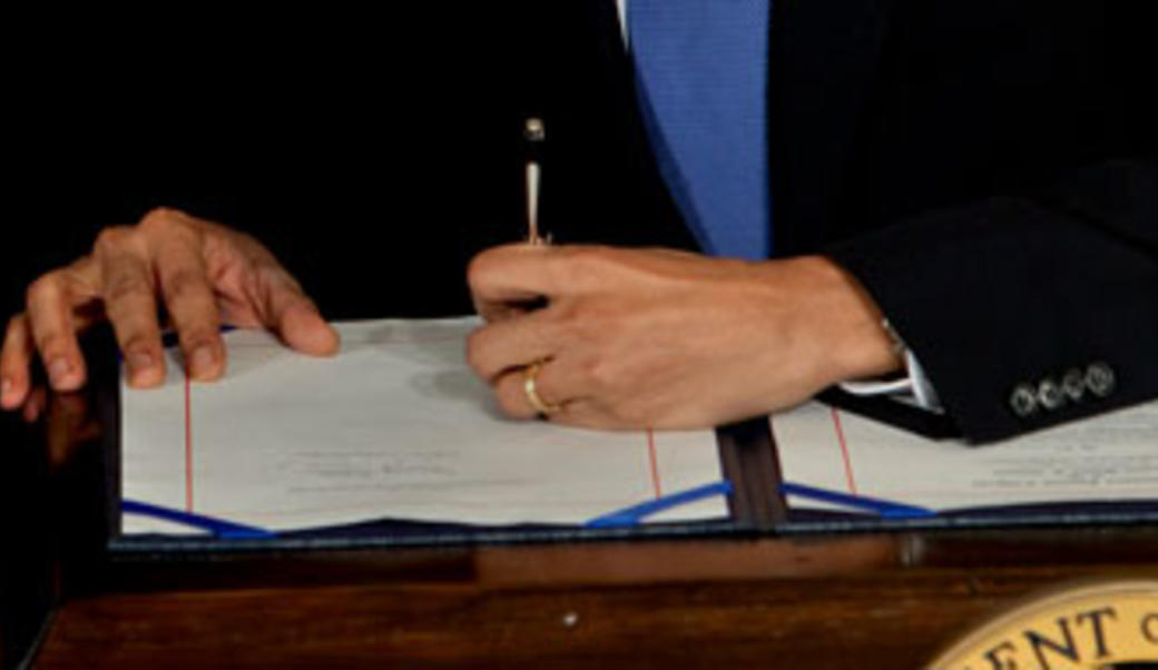 hand of Barack Obama signing bill