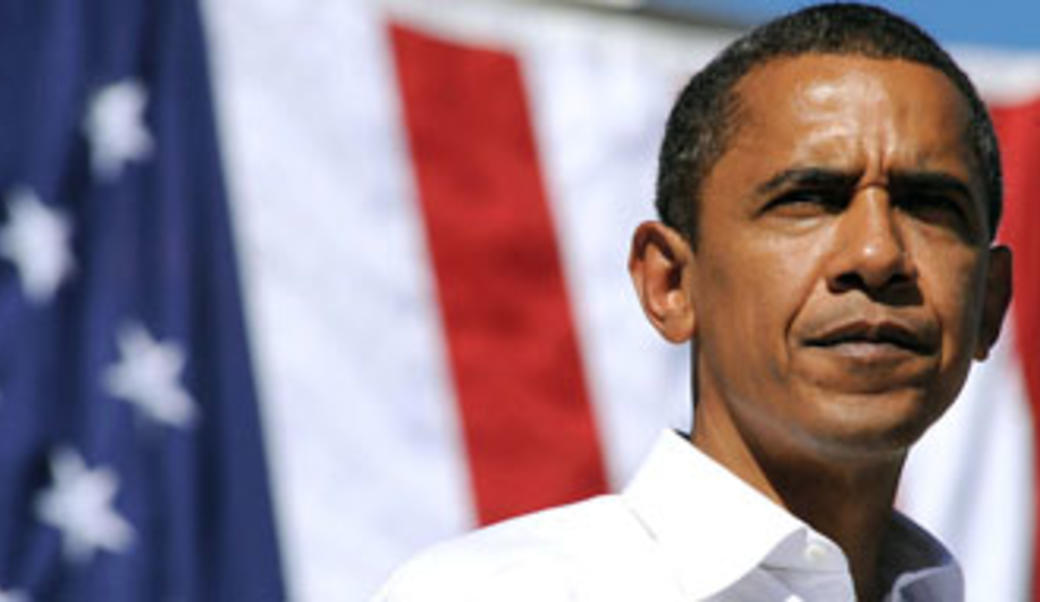 Former President Obama standing in front of an American flag