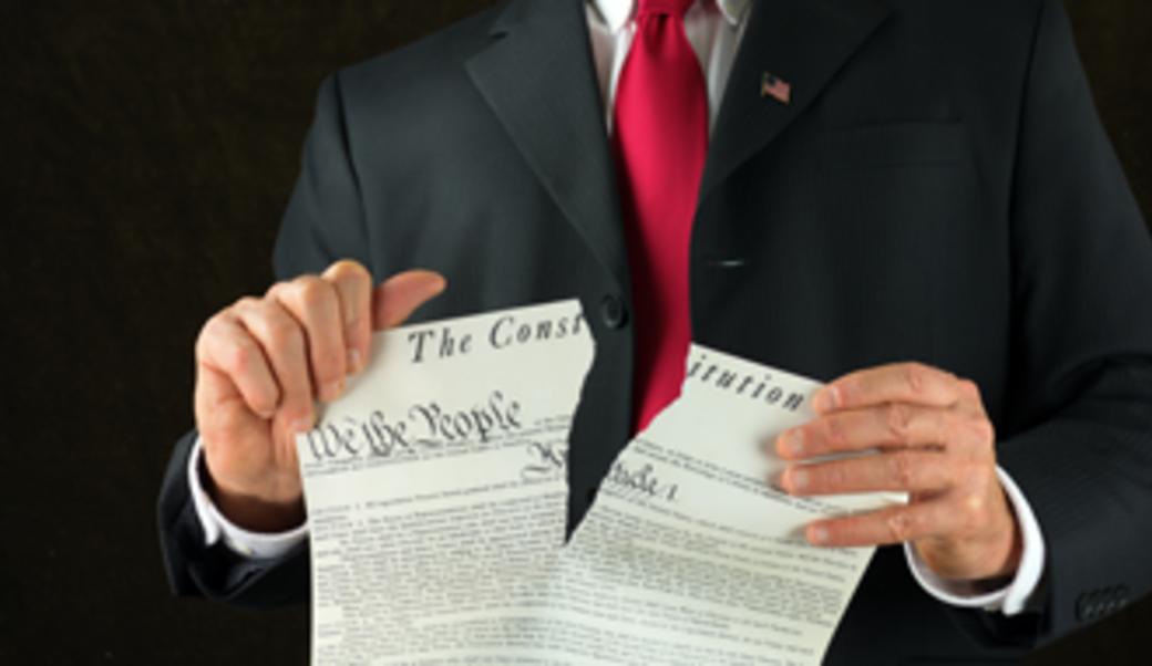 Man in suit with red tie ripping the constitution